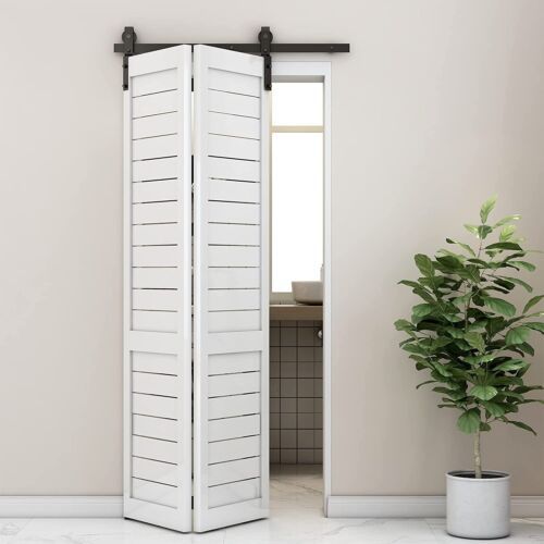 an open white door with shutters and a potted plant on the floor next to it