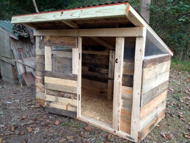 an outhouse made from wooden pallets in the woods