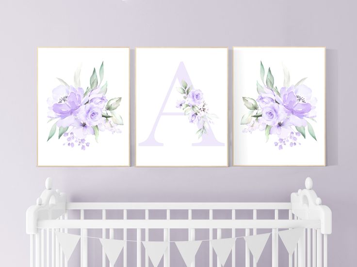 two purple flowers are hanging on the wall next to a crib in a baby's room