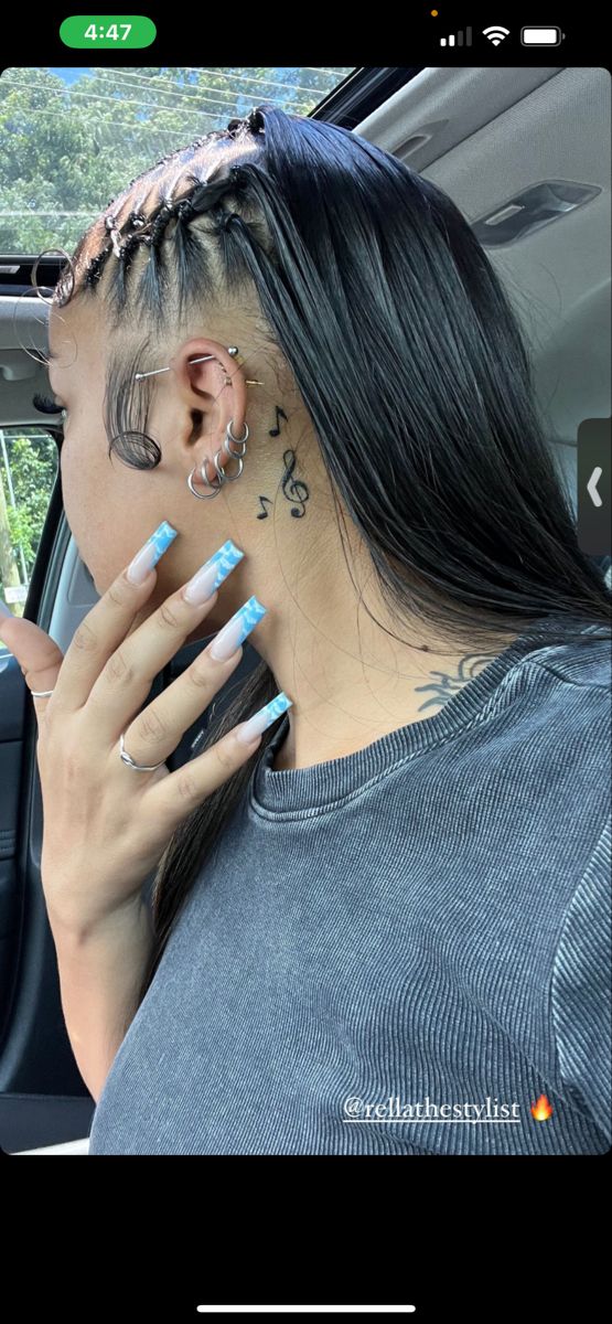 a woman with long black hair and piercings on her ear sitting in a car