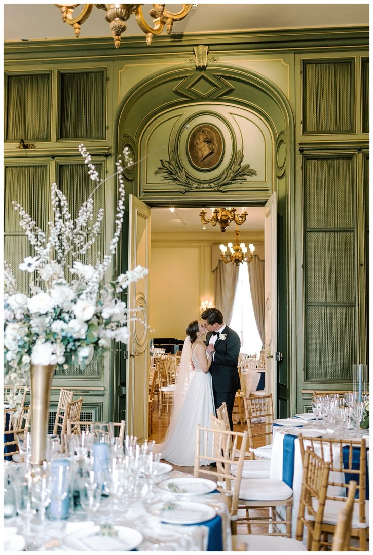 a bride and groom standing in front of a doorway at their wedding reception with tall floral centerpieces