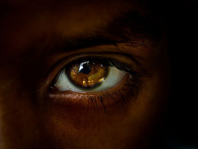 an eye is shown with the reflection of another person's face in its iris