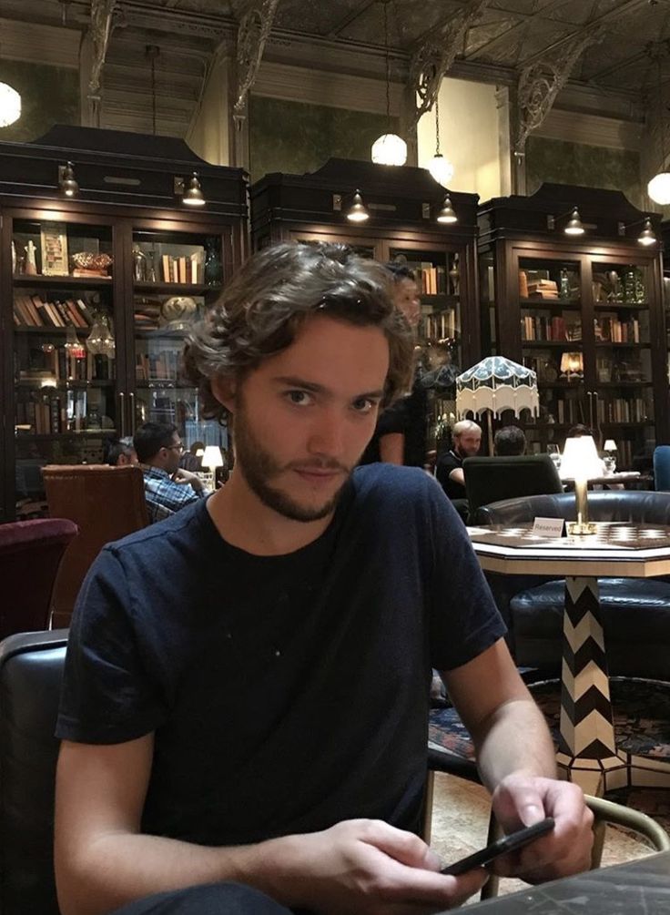 a man sitting at a table with a cell phone in his hand