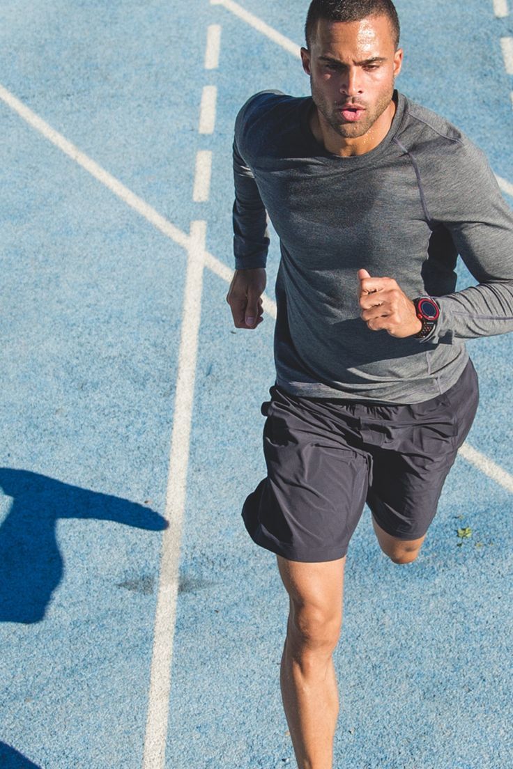 a man running across a blue tennis court with his shadow on the ground behind him