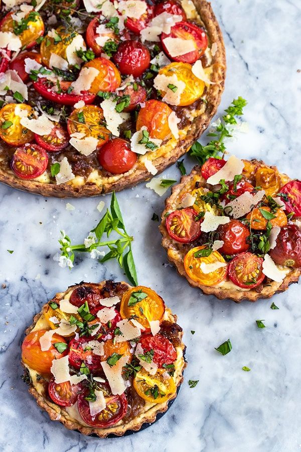 three small pizzas with different toppings on them sitting on a marble counter top