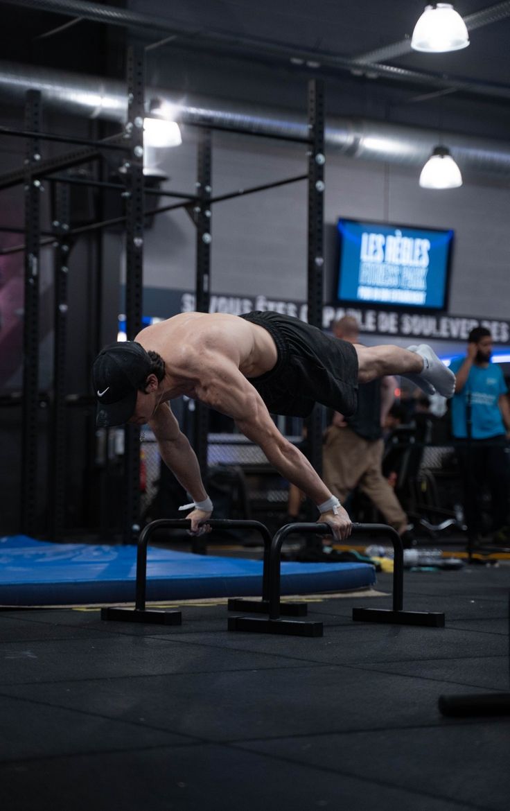 a man doing a handstand on a bar in a crossfit gym