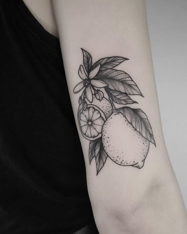 a woman's arm with an orange and lemon tattoo on the left inner arm