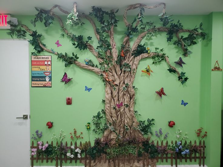 a green wall with a tree made out of paper flowers and butterflies on the branches