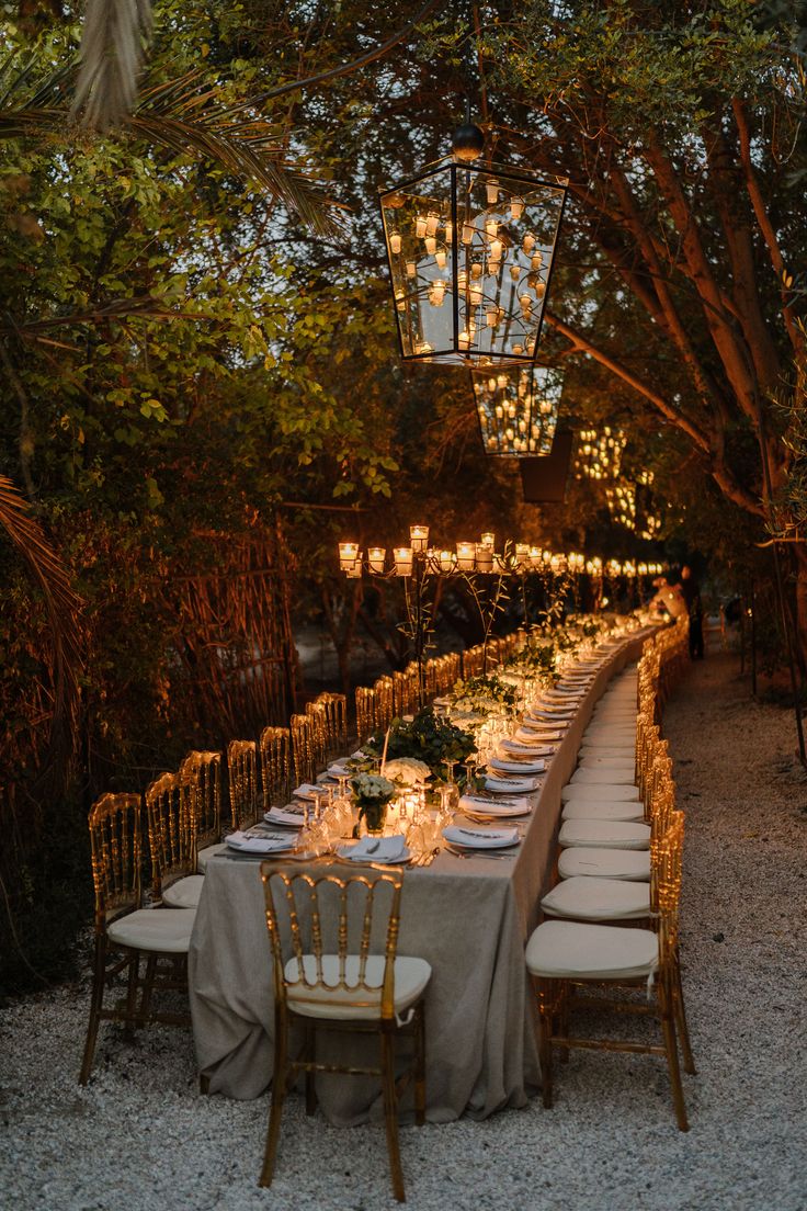 a long table is set up with candles and place settings for an outdoor dinner party