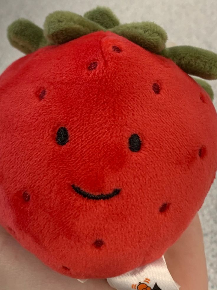 a close up of a stuffed strawberry on a person's head with a smile