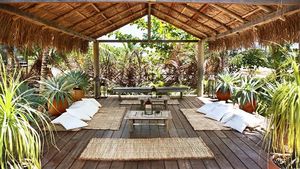 an outdoor covered patio with tables, chairs and potted plants on the deck area