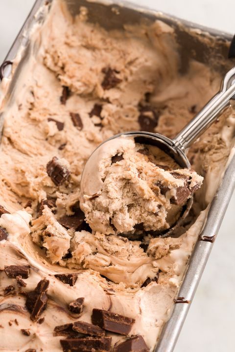 a scoop of ice cream in a pan with chocolate chunks on it and a spoon