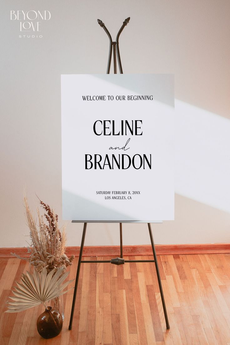 a welcome sign sitting on top of a wooden floor next to a potted plant