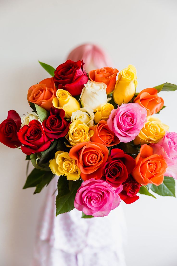 a woman holding a bouquet of colorful roses