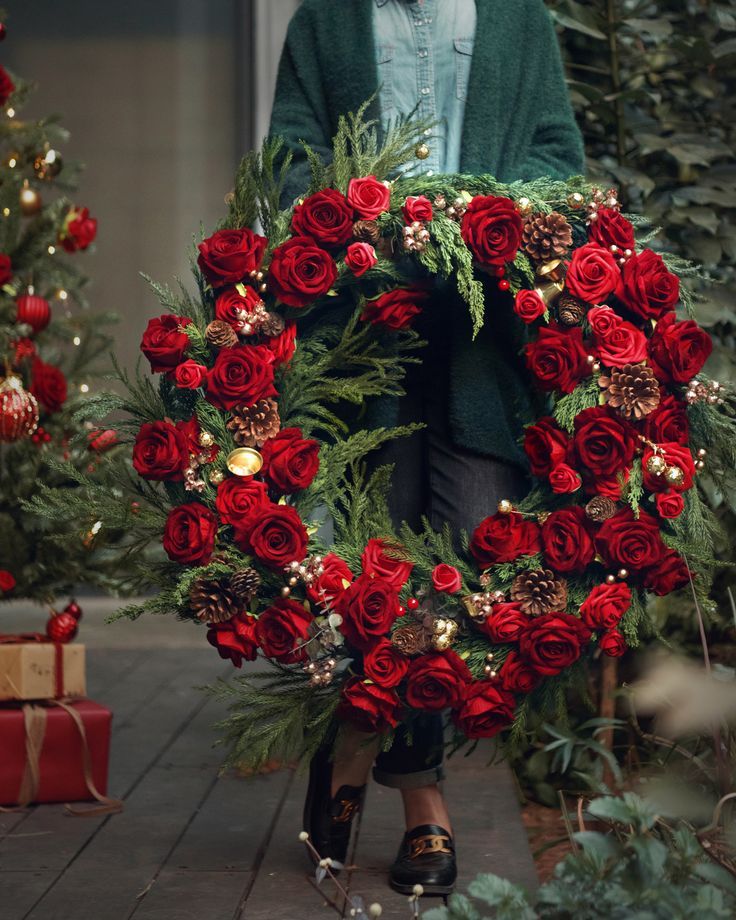 a woman holding a wreath with red roses