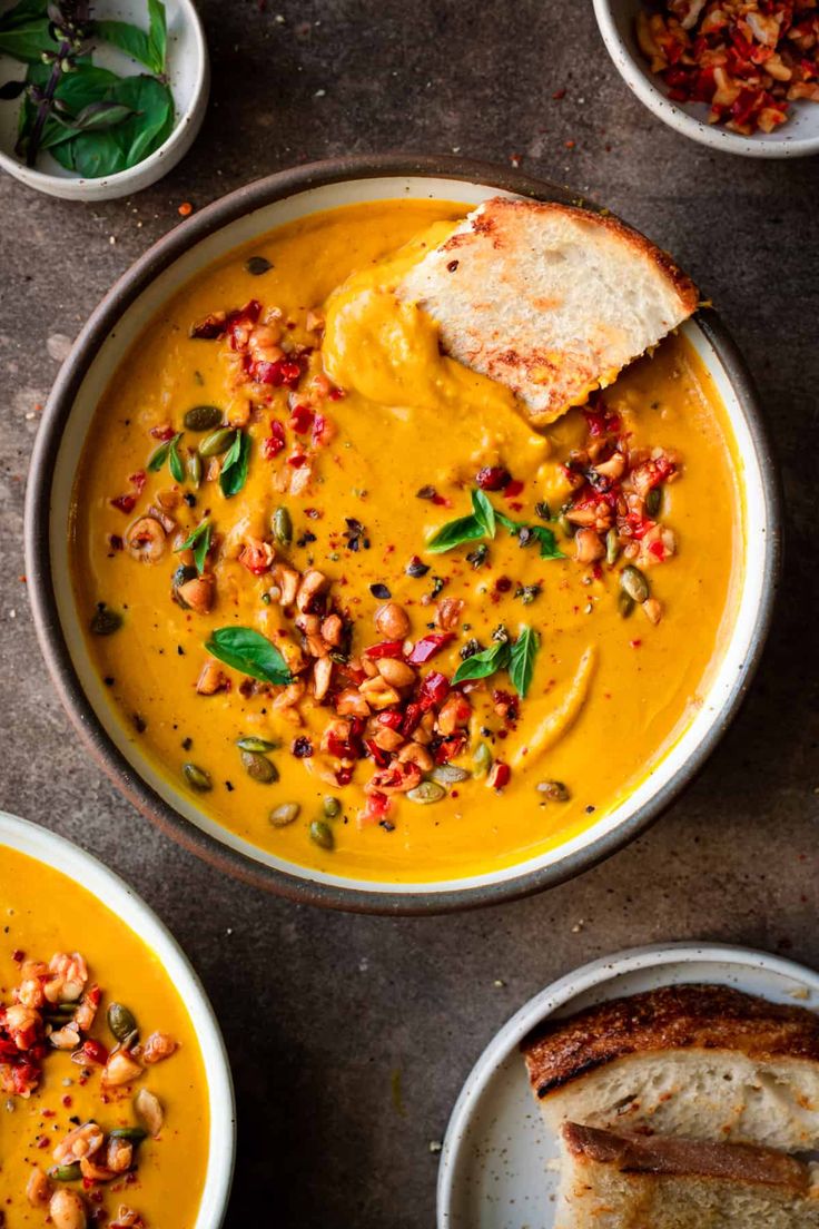 several bowls of soup with bread on the side