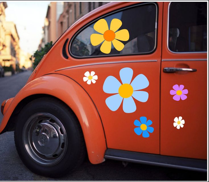 an orange vw bug with flowers painted on it's side in the street