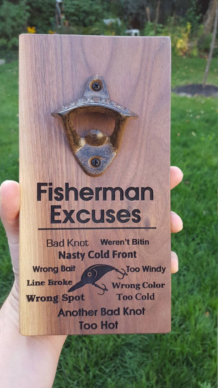 a person holding up a wooden plaque with an image of a fish and hook on it