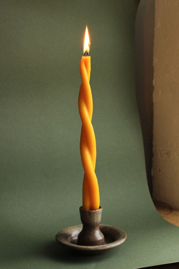 a lit candle sitting on top of a metal plate next to a green wall and floor