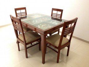 a glass table with four chairs around it in the middle of a floored room