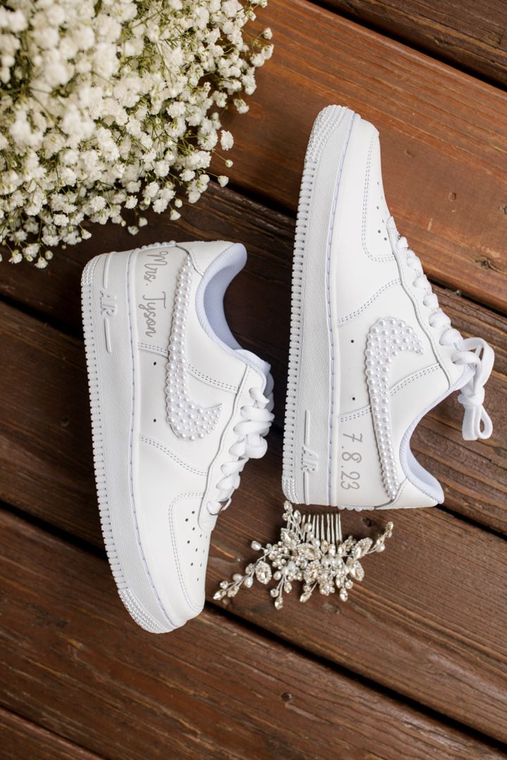 a pair of white sneakers sitting on top of a wooden floor next to flowers and baby's breath