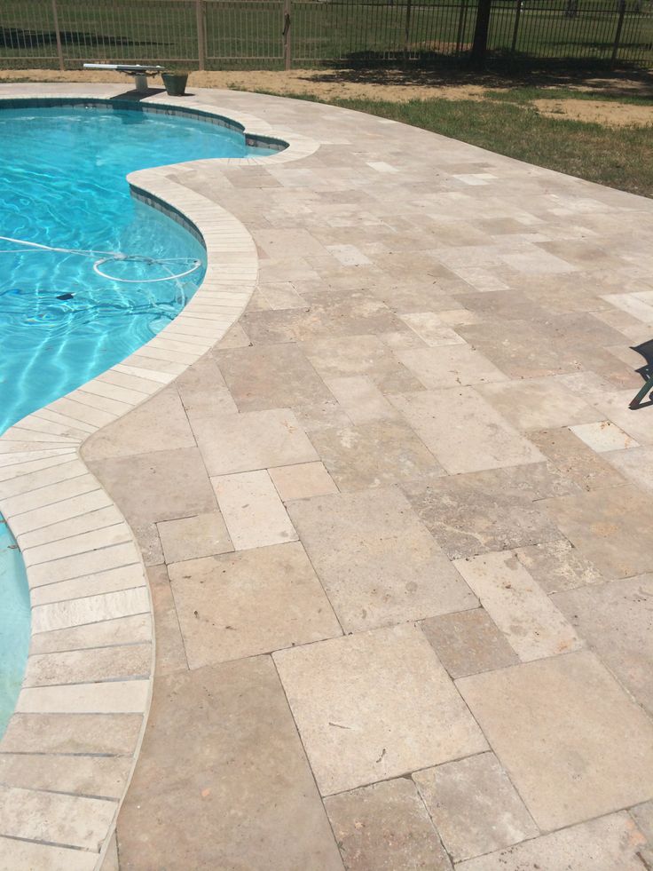 an empty swimming pool surrounded by stone pavers