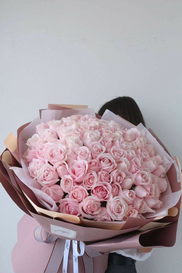 a woman holding a bouquet of pink roses