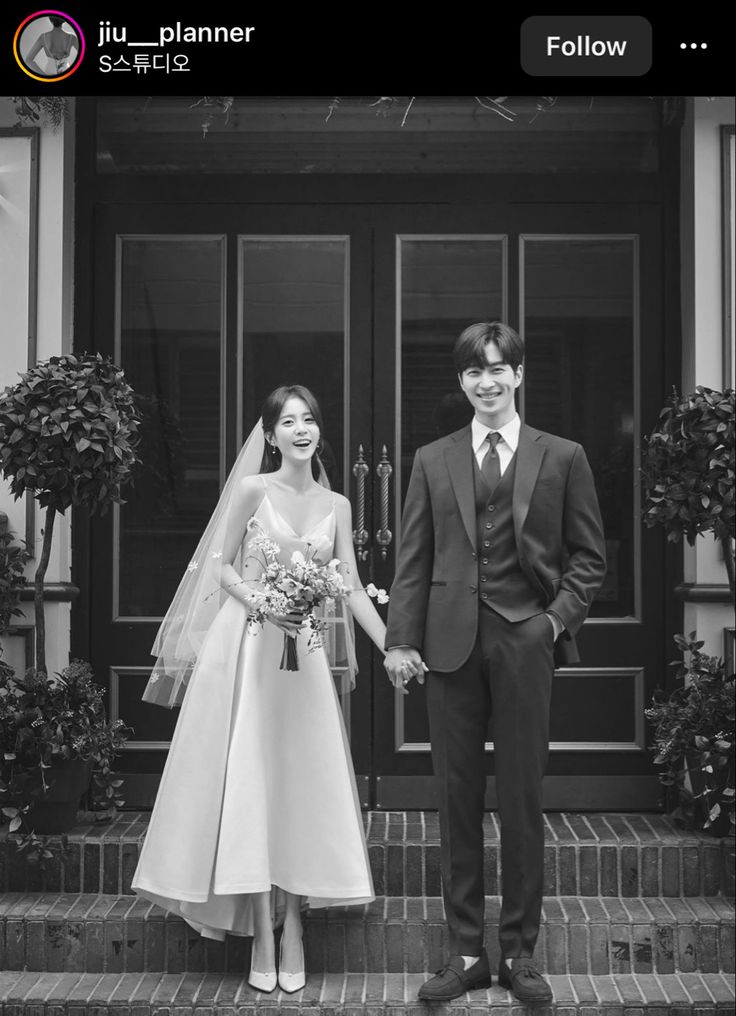 a bride and groom holding hands in front of a door with potted plants on either side