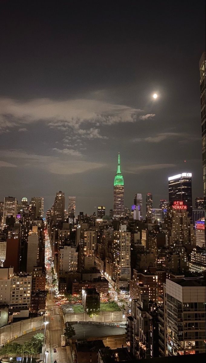 the city skyline is lit up with green and white lights at night, as seen from above