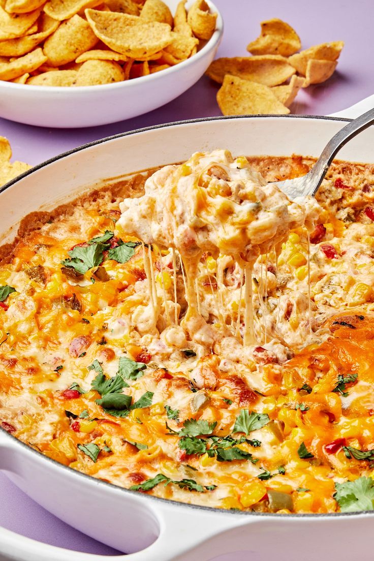 a white casserole dish filled with cheesy chicken and tortilla chips