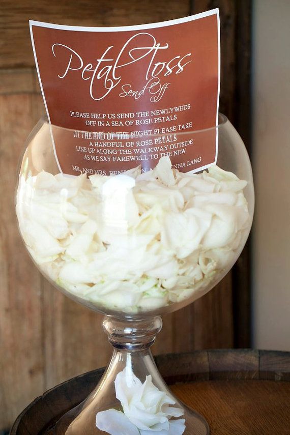 a bowl filled with white flowers sitting on top of a wooden barrel next to a sign