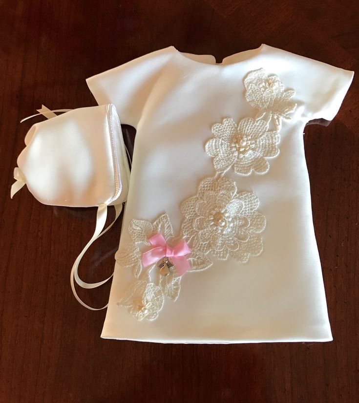 a white shirt with pink flowers on it and a small purse sitting next to it