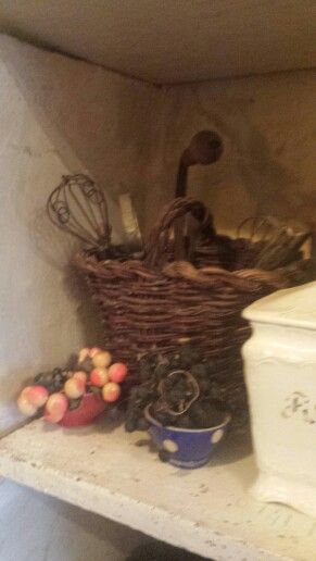 there is a basket with utensils and other items on the shelf next to it