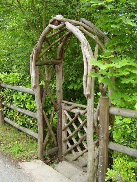 an arch made out of branches on the side of a road next to some trees