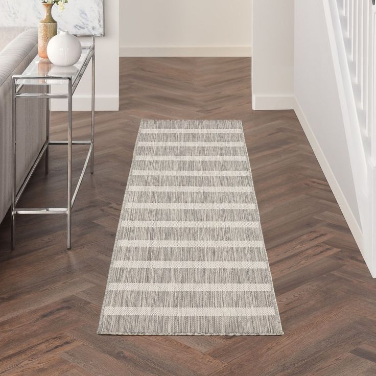 a white and gray striped rug on the floor next to a stair case in a living room