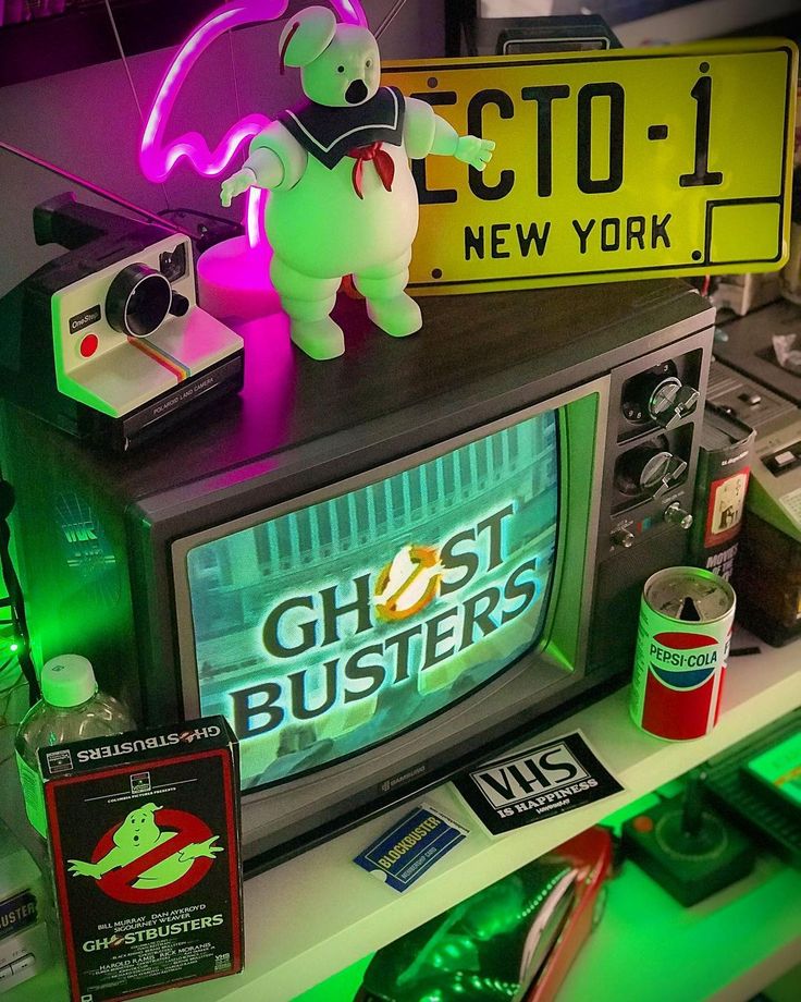 an old television set with ghostbusters on top and neon signs above the tv