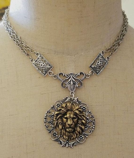 This lion choker necklace is designed and handcrafted by Viviana Jewelry Designs.  The pendant is the finest sterling silver plated brass vintage style filigree and bronze lion stamping that was made in the USA.  the chain and other jewelry findings are silver plated.  This is a stunning necklace that is certainly an eye catcher.  My lion necklaces continue to be very popular with my customers.   This is a choker necklace which typically is 14 inches long, however, everyone's necklace size is different.  Please specify what length that you want your choker necklace to be when ordering.   Will ship priority, but if you want priority or, please contact me directly prior to ordering.   Thank you for shopping Viviana Jewelry Designs.  Have a blessed and wonderful day.   Best, Vivian Luxury Silver Warrior Style Jewelry, Luxury Ceremonial Necklaces With Historical Design, Luxury Carved Necklaces For Wedding, Luxury Historical Ceremonial Necklaces, Luxury Medieval Jewelry With Intricate Design, Luxury Ornate Hand-set Necklace, Luxury Medieval Silver Jewelry, Luxury Ornate Metal Necklace, Luxury Ornate Metal Necklaces