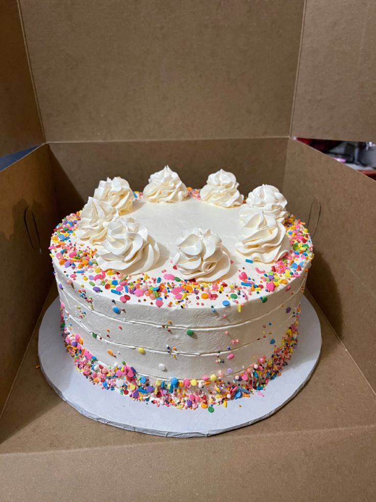 a cake in a box with sprinkles and white frosting