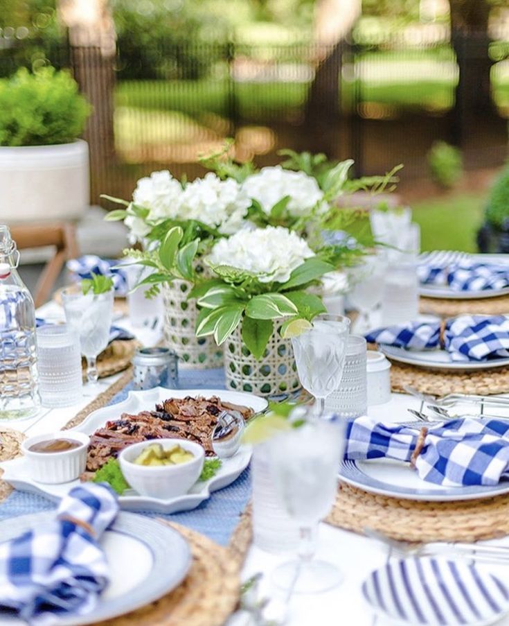 a table set with plates, bowls and vases filled with flowers on top of it