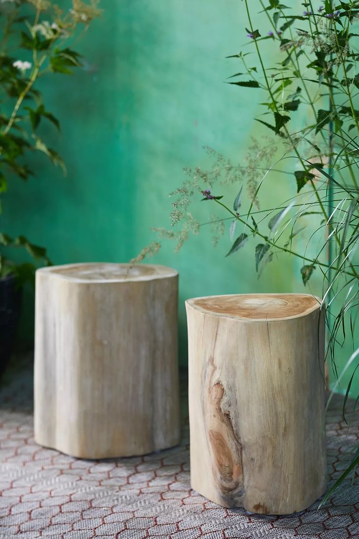 two wooden vases sitting on top of a table next to some plants and flowers