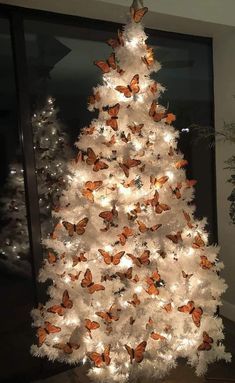 a white christmas tree with orange butterflies on it