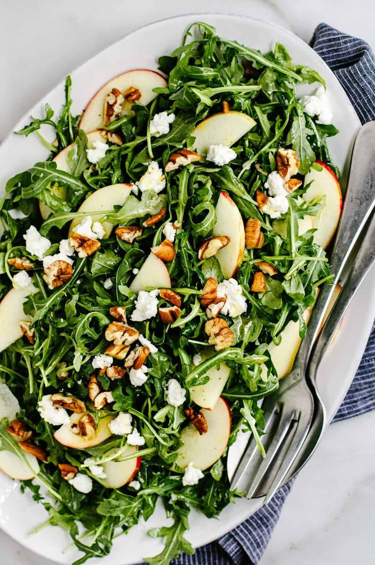 a white plate topped with green salad and apples