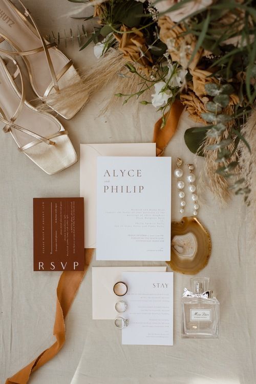 the wedding stationery is laid out on top of the table with shoes and accessories