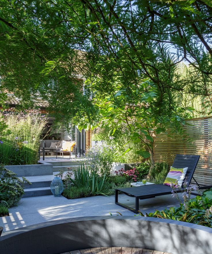 an outdoor patio with seating and trees in the foreground, surrounded by greenery