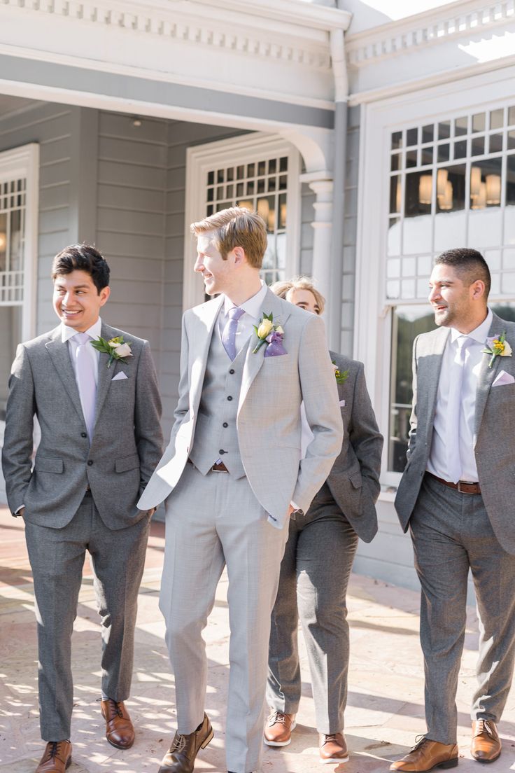 a group of men standing next to each other wearing suits and ties on the street