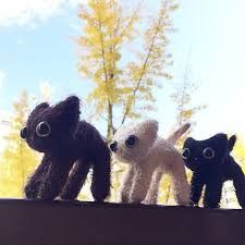 three small stuffed animals sitting on top of a wooden table in front of some trees