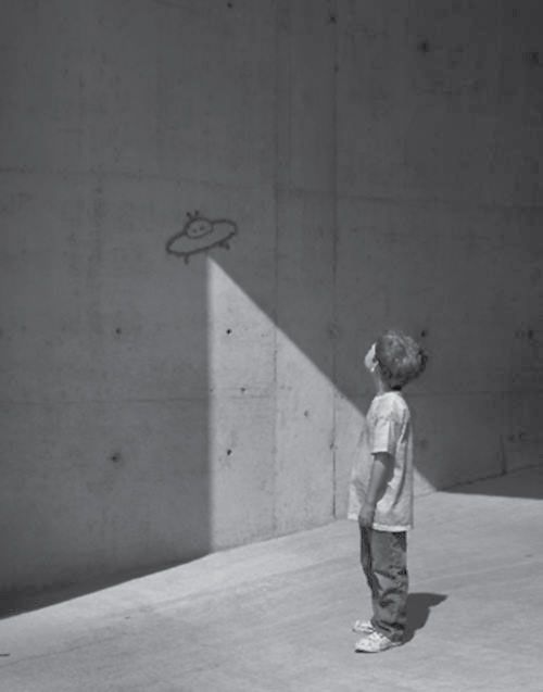 a young boy standing in front of a concrete wall with a drawing on it's side