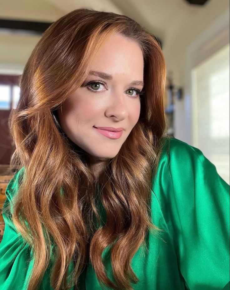 a woman with long brown hair wearing a green blouse