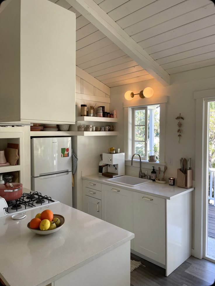 a bowl of fruit sitting on top of a kitchen counter next to an open door