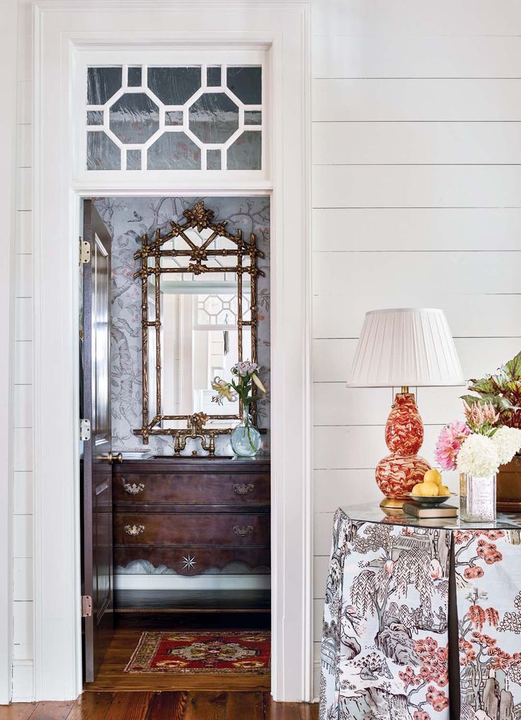 a room with a dresser, mirror and lamp on the side walk in front of it